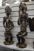 A pair of African carved stone figures, one female with suckling baby and the other depicting male.