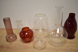 An assorted collection of clear and coloured glass oil lamp shades and chimneys, including a