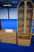 A nice quality modern beech effect low cupboard and arch top display, labelled Holtkamp