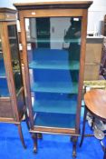 A late 19th or early 20th Century mahogany display cabinet of narrow proportions, having scroll
