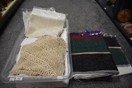 A collection of vintage table linen, including damask tablecloths, wool rug and macrame shawl.