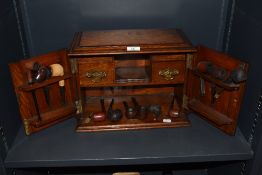 An early 20th century gents smokers cabinet with integrated pip racks, drawers and a selection of