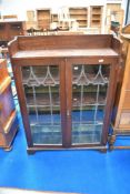 A late 19th or early 20th Century oak bookcase having shaped leaded glass doors, in the Art