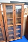 A modern pine glass fronted slim bookcase
