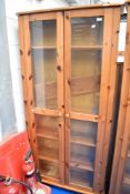 A modern pine glass fronted slim bookcase