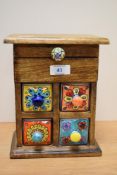 An unusual hardwood and ceramic miniature set of drawers, for jewellery and trinkets, with four