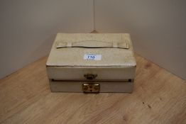 A pale double tier jewellery box containing an assortment of costume jewellery including large