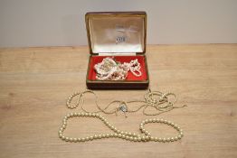 A red faux crocodile jewellery box containing an assortment of imitation pearl necklaces and a