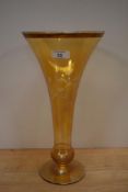 A vintage tinted glass vase of drawn trumpet form with basel knop, wheel engraved with foliate