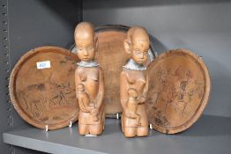 Three carved plaques having traditional scenes of people and animals and two carved women holding