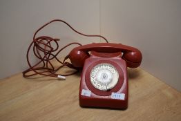 A vintage red rotary telephone.