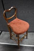A Victorian correction chair of mixed woods, having balloon and rail back, with later upholstered