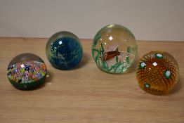 Four assorted paperweights including a Millefiori set onto a green background, a multi cane fish,