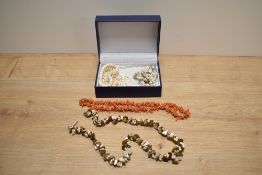 A collection of necklaces comprising two sea-shell examples, a coral example, a row of freshwater