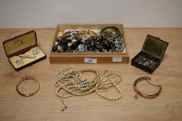 An assortment of costume jewellery including faux pearls, a mother-of-pearl cufflink and tie clip