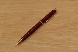 A Waterman propelling pencil in crimson lacque with gold trim.