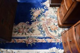 A vintage Chinese carpet square having blue ground with floral pattern and fringed edge, approx