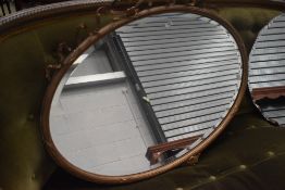 An Edwardian oval mantel mirror, having gilt plaster frame with bow detail, approx 95cm by 74cm.