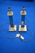 A pair of modern brass and chrome column formed table lamps