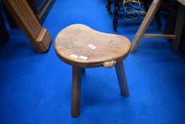 An Arts and Crafts golden oak three legged stool by 'Mouseman' Thompson, having typical carved mouse