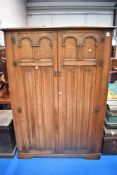 An early 20th century priory style oak double wardrobe having linen fold doors, width approx 129cm.