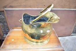 A vintage brass coal helmet and poker and tongues.
