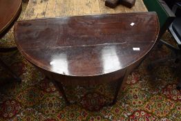 A 19th Century mahogany fold over card table of demi lune form having line inlay , on square tapered