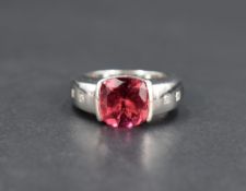 A pink tourmaline solitaire ring in a tension set mount to diamond set heavy set shoulders on an