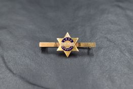 A yellow metal and enamel long service award bar brooch stamped 18ct having inset diamond and