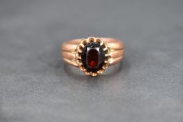 A large signet style ring, having a central oval cut red gemstone possibly garnet with moulded
