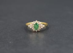 An emerald and diamond cluster ring, the central oval cut emerald measuring approximately 0.40ct