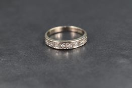 A white metal half eternity ring stamped 18ct having eight diamond chips in square mounts, size