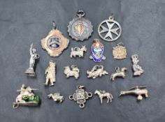 A collection of silver and white metal charms including a silver shield medallion marked 'N.S.C