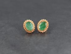 A pair of 9ct gold emerald stud earrings, the oval cut emeralds in bezel settings with twisted