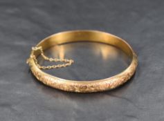 A 9ct rose gold hinged bangle having engraved scroll decoration, approx 60mm diameter & 7.6g