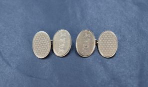 A pair of 9ct gold cufflinks having engine turned decoration and monograms to oval panels with chain