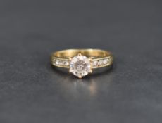 A cubic zirconia single stone ring, the round cut cubic zirconia flanked by three cubic zirconia