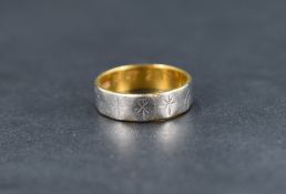A 22ct gold wedding band having a white metal finish to the outside with repeating star burst