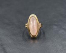A pink quartz cabouchon ring having an oval collared mount to butt shoulders on an 8ct gold loop,
