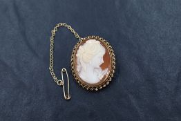 A conch shell cameo brooch depicting a maiden in profile, in a decorative 9ct gold mount with safety