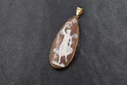A pear shaped shell cameo pendant, depicting a winged dancing maiden with flora and fauna, set in