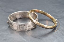 A silver hinged bracelet having engraved scroll decoration, approx 60mm diameter and a narrow silver