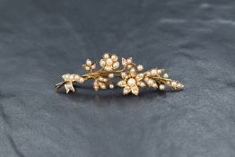 A yellow metal and seed pearl spray brooch, the arched floral spray set with seed pearls of