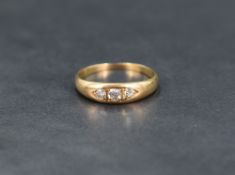 A three stone gypsy style diamond ring, the central diamond measuring approximately 0.07ct flanked