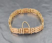 A yellow metal three bar gate bracelet marked 15, having a safety chain to clasp, approximately 17cm