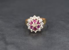 A diamond and ruby cluster ring, the central illusion set diamond with a six ruby surround having