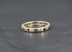 A 9ct gold full eternity ring, set with alternating round cut green and colourless paste, ring