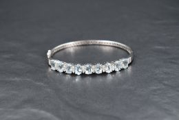 An 18ct white gold, aqua marine and diamond hinged bangle having nine brilliant cut aqua marines