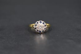 A diamond and sapphire cushion cluster having a small central diamond, approx 0.064ct within a