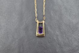 An modern amethyst pendant, the emerald cut amethyst set in an 18ct gold open rectangular setting,